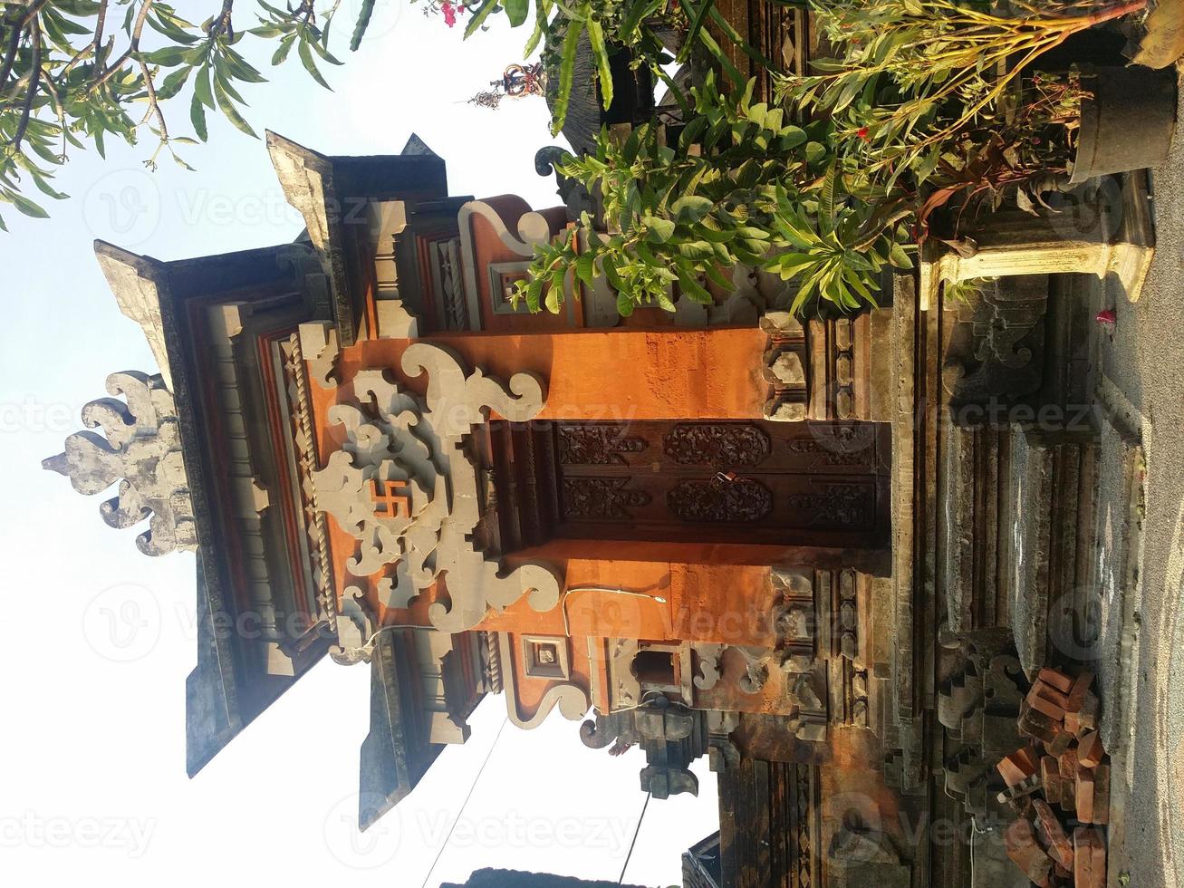 Balinees traditioneel gebouw in de vorm van een ingang gemaakt van steen met een achtergrond van blauwe lucht en groen foto
