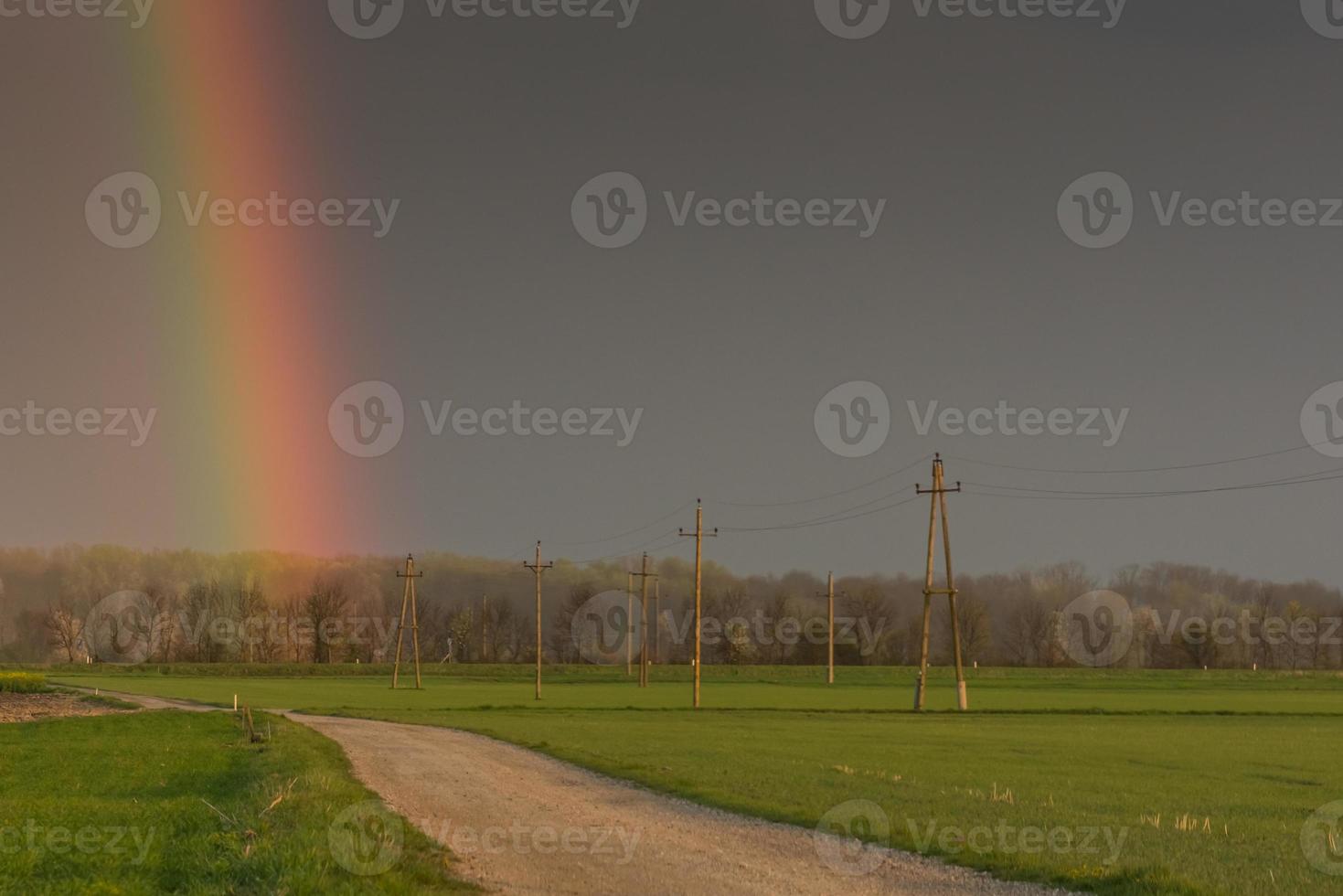 prachtige groene velden met hoogspanningsmasten en een regenboog foto