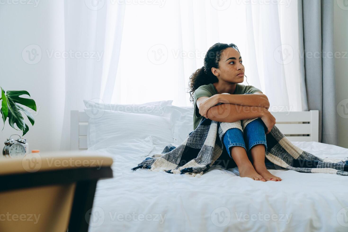 overstuur Afro-Amerikaanse vrouw wikkelde zichzelf in een deken en kijkt opzij foto