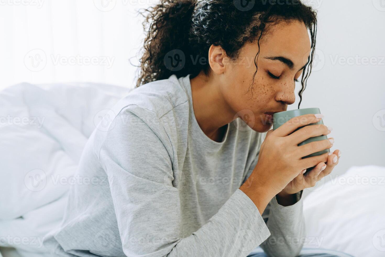 Afrikaanse vrouw die koffie drinkt op het bed foto