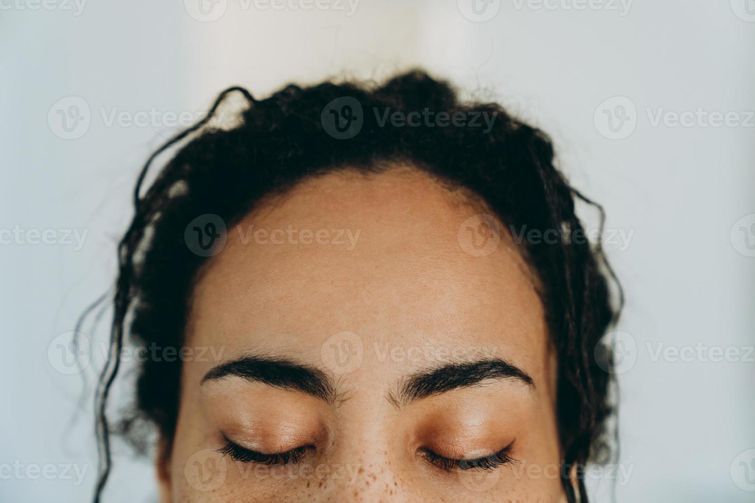 zwarte vrouw die met gesloten ogen poseert terwijl ze thuis tijd doorbrengt foto