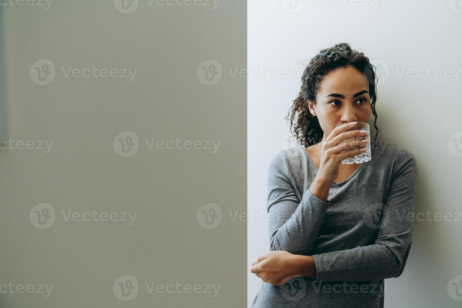 jonge zwarte vrouw die water drinkt tijdens tijd thuis doorbrengen? foto