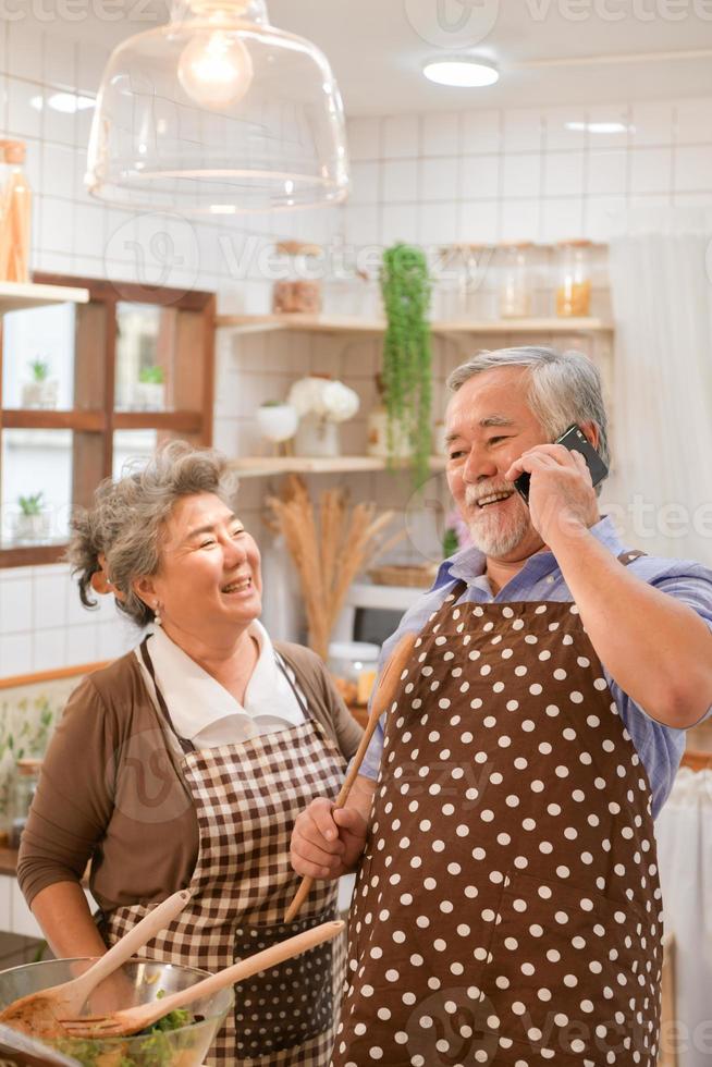 de bejaarde stellen in de keuken om vrolijk te koken en te eten in de moderne keukens. foto