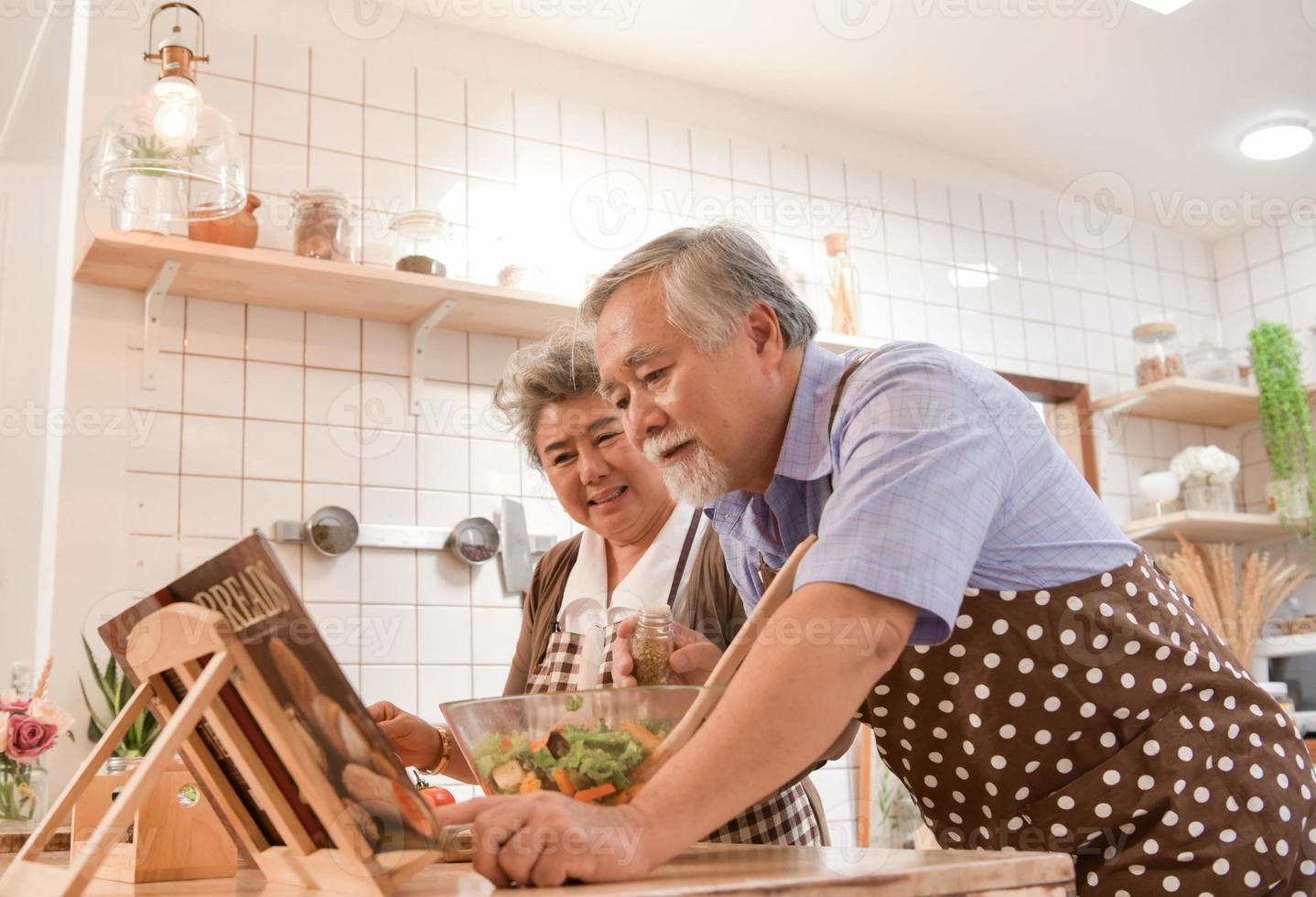 de bejaarde stellen in de keuken om vrolijk te koken en te eten in de moderne keukens. foto