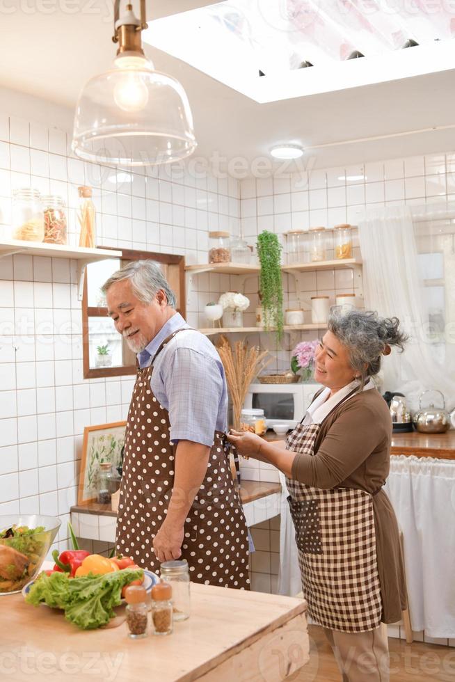 de bejaarde stellen in de keuken om vrolijk te koken en te eten in de moderne keukens. foto