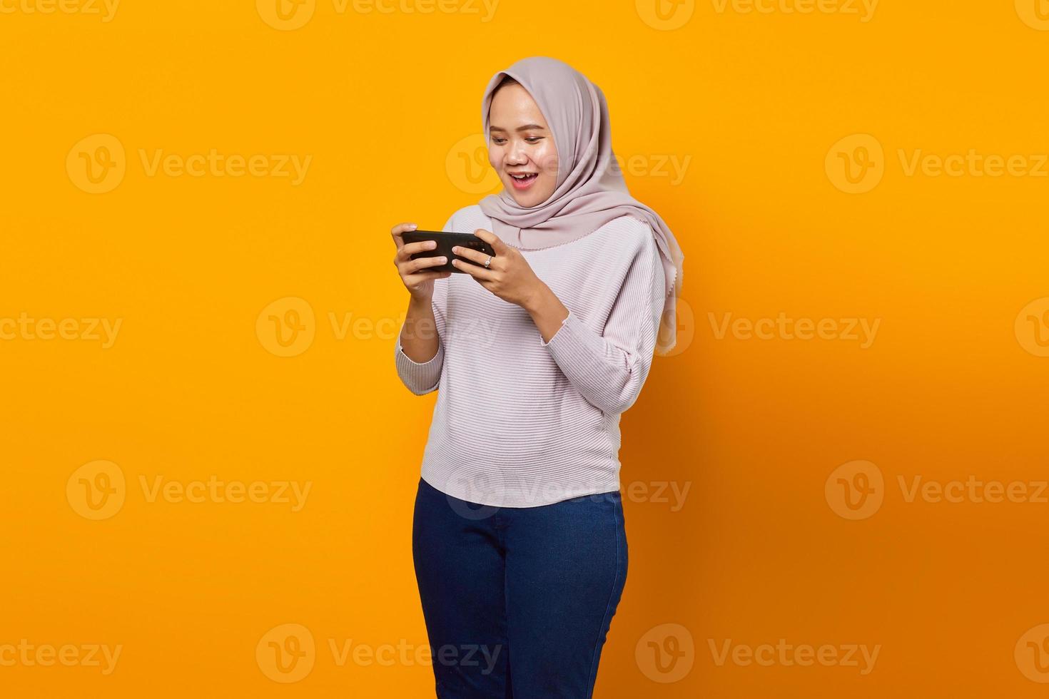 portret van gelukkige jonge aziatische vrouw die videogame speelt op mobiele telefoon foto