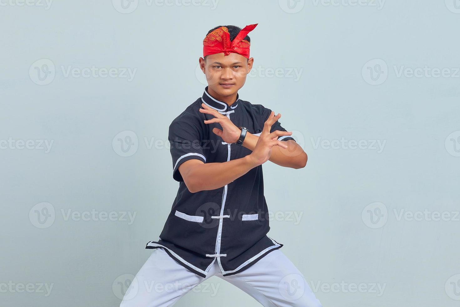 Foto van knappe jonge sportman gekleed in kimono-oefening in karate geïsoleerd over grijze achtergrond