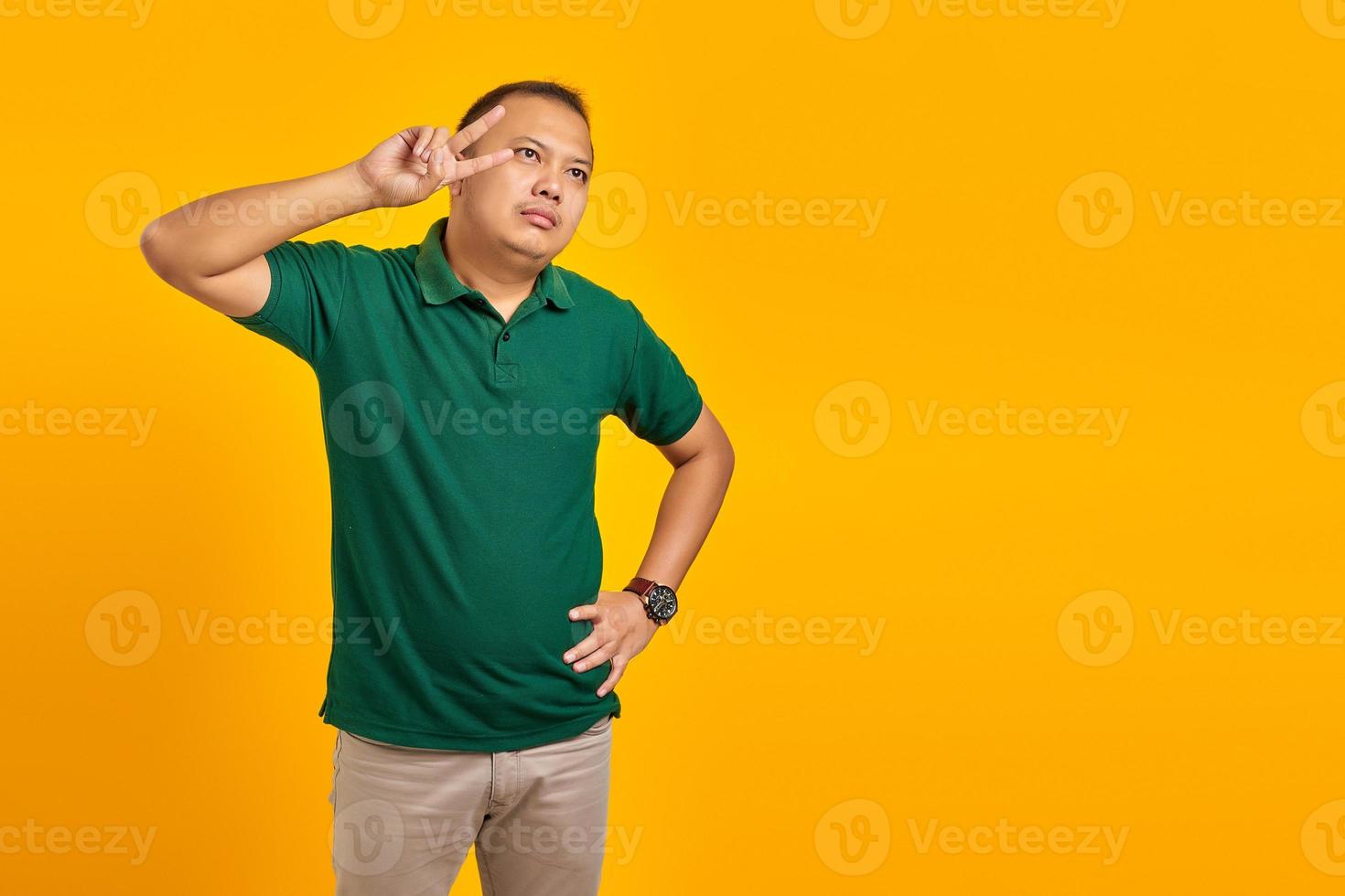 portret van trieste jonge Aziatische man die vredesteken maakt met vingers over gele achtergrond foto