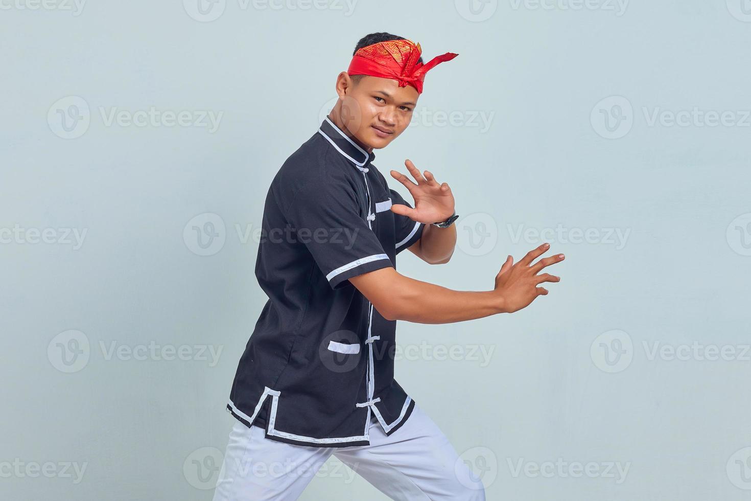 Foto van knappe jonge sportman gekleed in kimono-oefening in karate geïsoleerd over grijze achtergrond