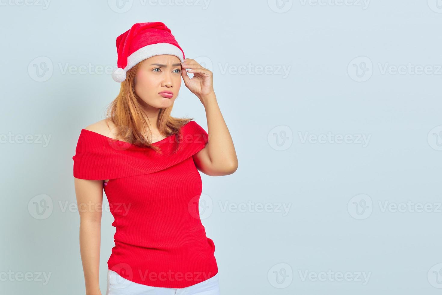 peinzende jonge aziatische vrouw die serieus nadenkt over een vraag en kerstjurk draagt foto