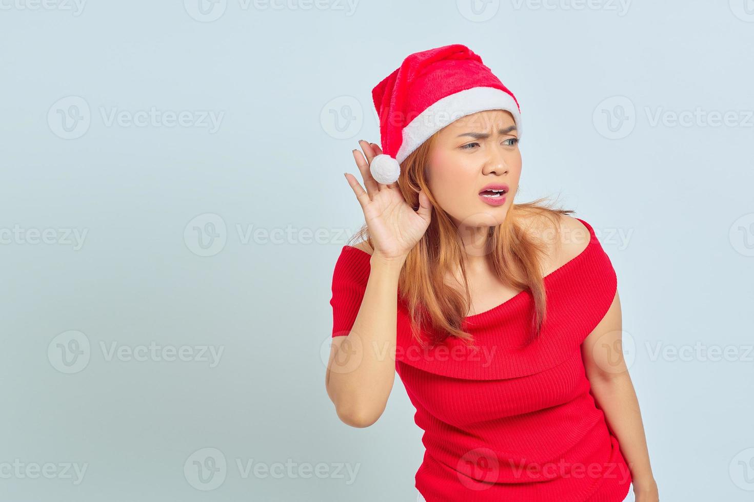portret van een jonge aziatische vrouw die een kerstjurk draagt en naar een geheim gesprek luistert foto