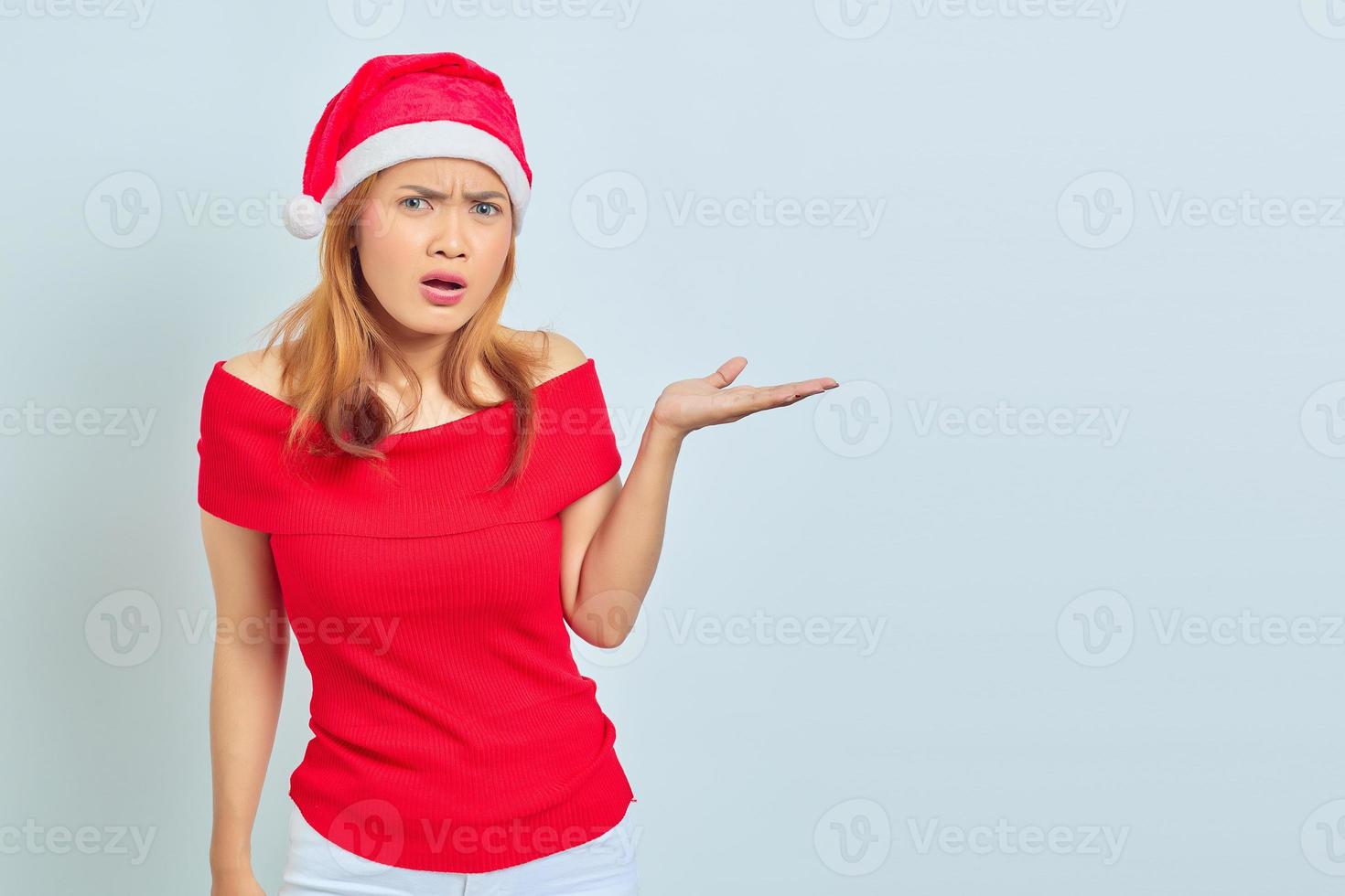 portret van een jonge aziatische vrouw die een kerstjurk draagt en iets met handpalmen laat zien met een geschokte uitdrukking foto