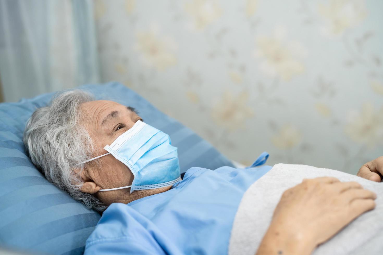 aziatische senior of oudere oude dame vrouw patiënt draagt een gezichtsmasker nieuw normaal in het ziekenhuis ter bescherming van de veiligheidsinfectie covid-19 coronavirus. foto