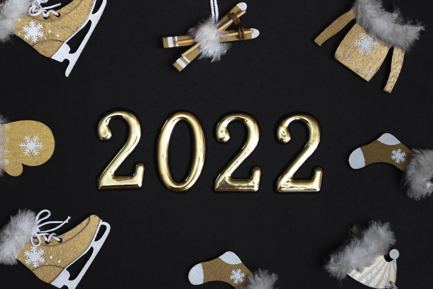 bovenaanzicht plat nieuwjaarsmodel op zwarte achtergrond met cijfers en nieuwjaarsdecor. nieuwjaar 2022, met kopieerruimte foto