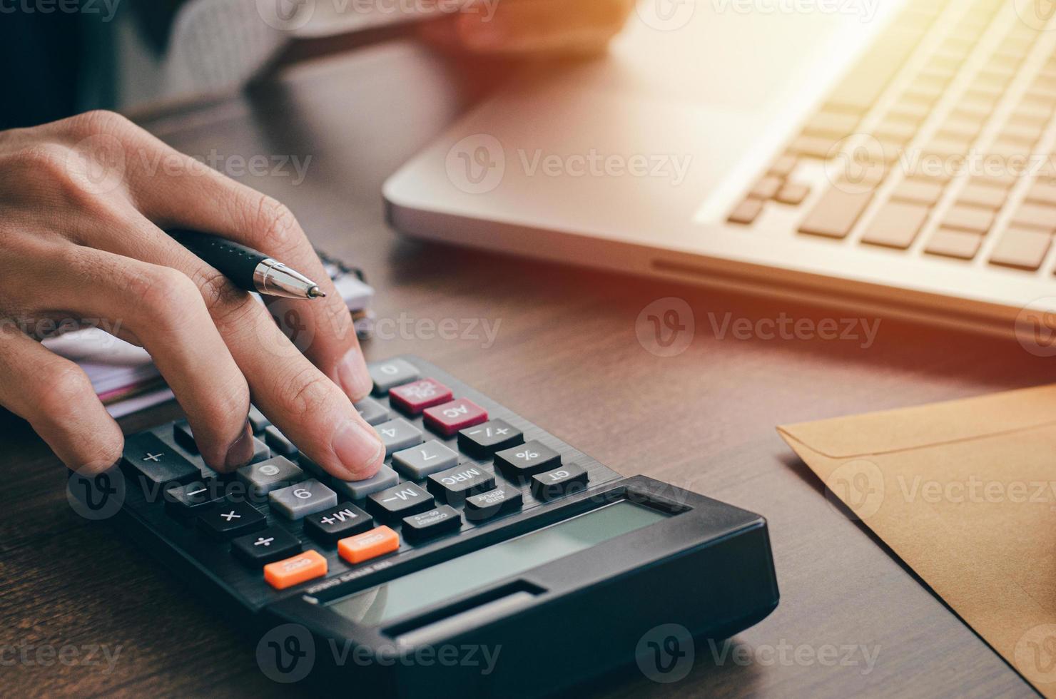 jonge mannelijke belegger die investeringskosten berekent met een rekenmachine en bankbiljetten in de hand houdt. met zaken, investeringen, belasting foto