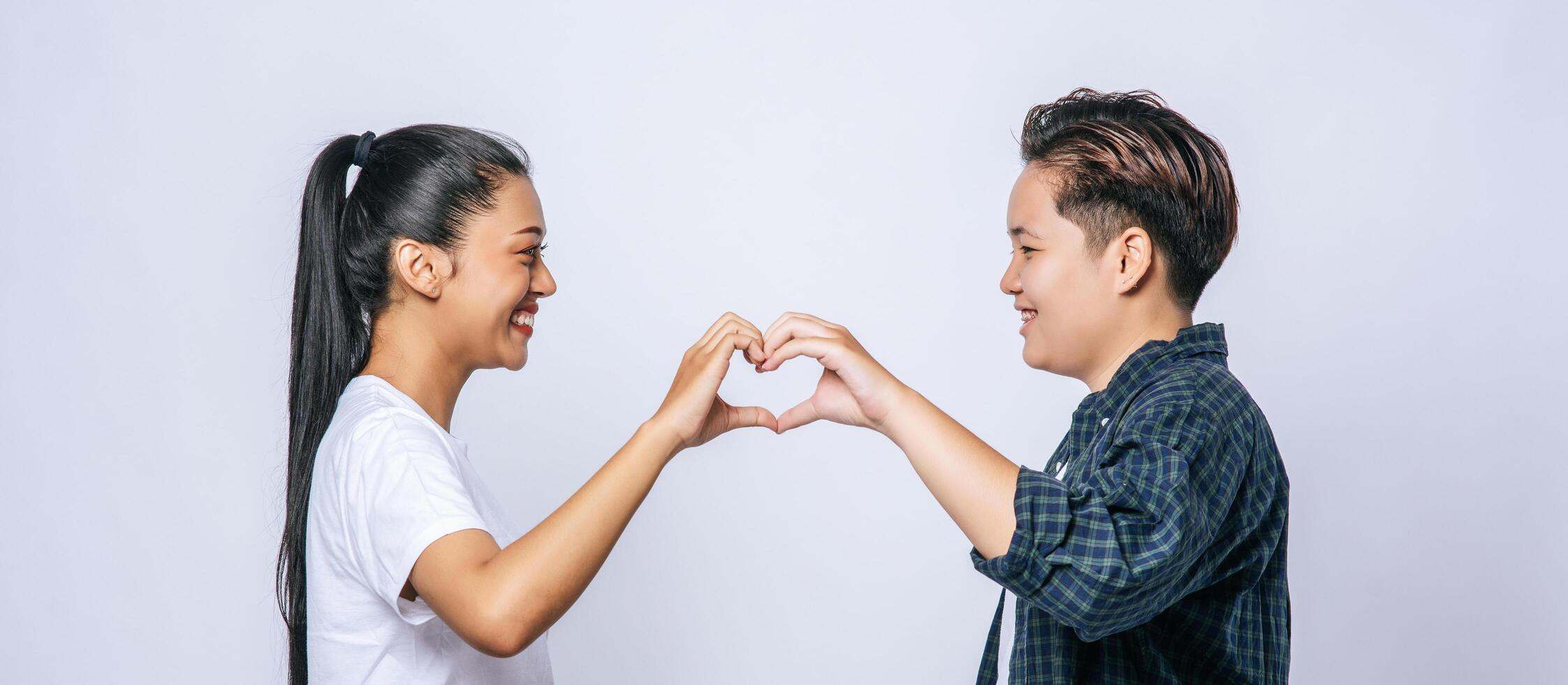 twee jonge vrouwen houden van elkaar handteken hartvorm. foto