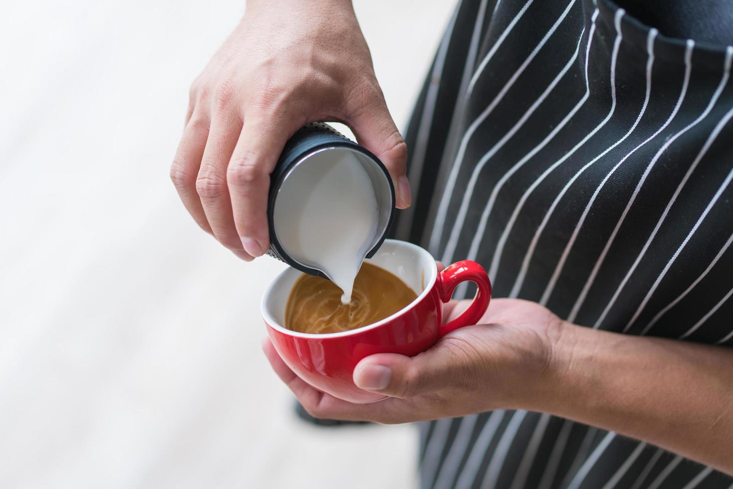 barista die latte of cappuccino maakt koffie schenkt melk foto