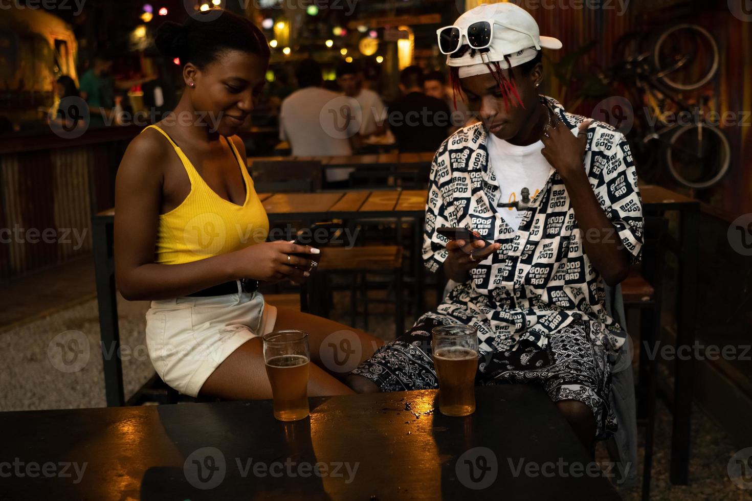 jong stel negeert elkaar in een bar tijdens het gebruik van mobiele telefoons. foto