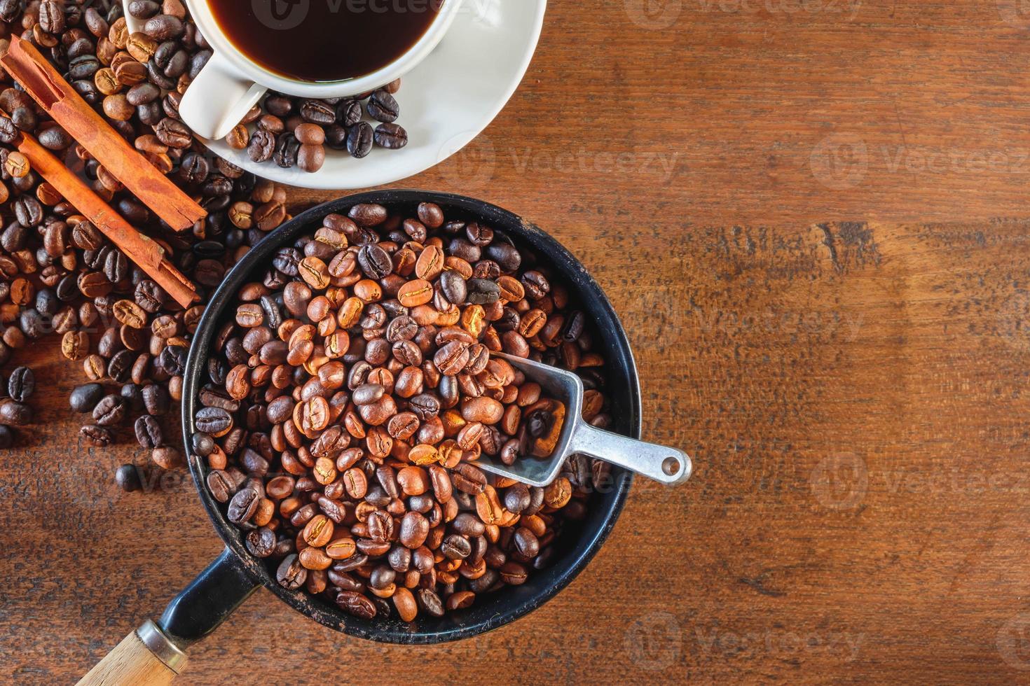 bovenaanzicht van koffiebonen geroosterd in een pan en een koffiekopje. foto