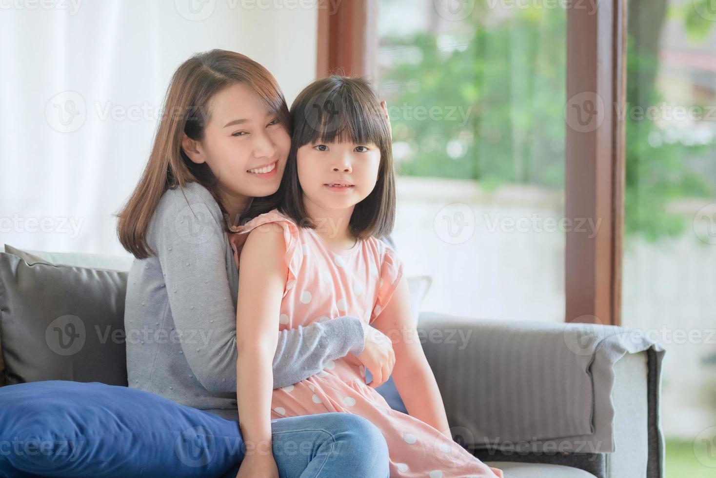 Aziatische moeder voelt geluk tijdens het knuffelen van haar schattige dochter met liefde en zorg thuis foto