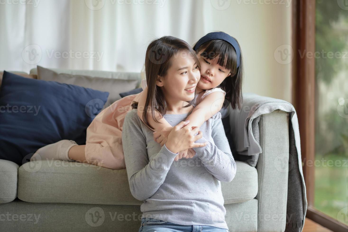 Aziatische moeder vrijt met warme knuffel haar schattige dochter thuis foto