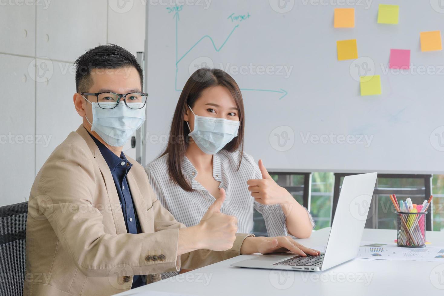 zakelijke werknemers die tijdens het werk op kantoor een masker dragen om de hygiëne te behouden, volgen het bedrijfsbeleid. preventief tijdens de periode van epidemie van coronavirus of covid19. foto