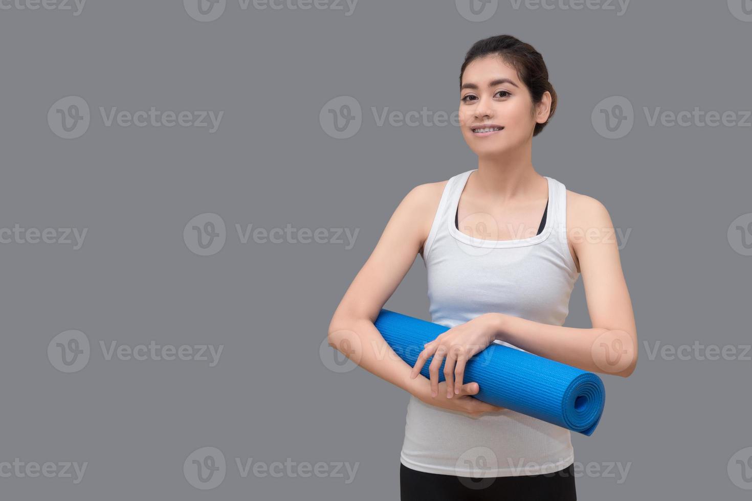 aziatische vrouw die haar yogamat houdt bij gezonde sportgymnastiek. yoga en meditatie hebben goede voordelen voor de gezondheid. fotoconcept voor yogasport en een gezonde levensstijl foto