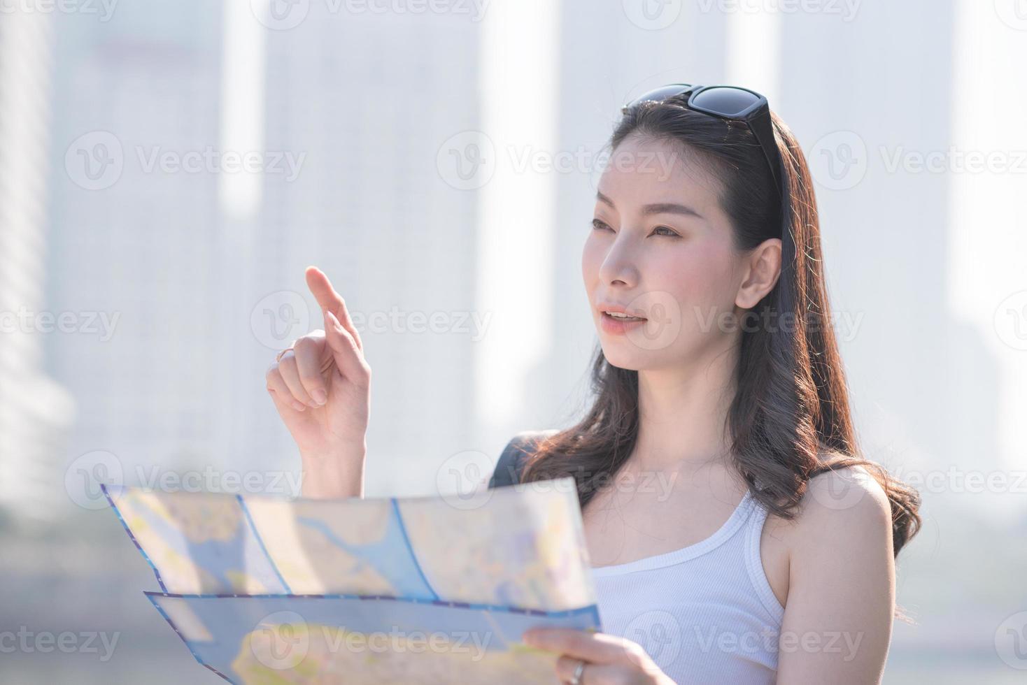 mooie aziatische solo-toeristische vrouw die naar de kaart kijkt op zoek naar toeristen die bezienswaardigheden bezoeken. vakantie reizen in de zomer. foto