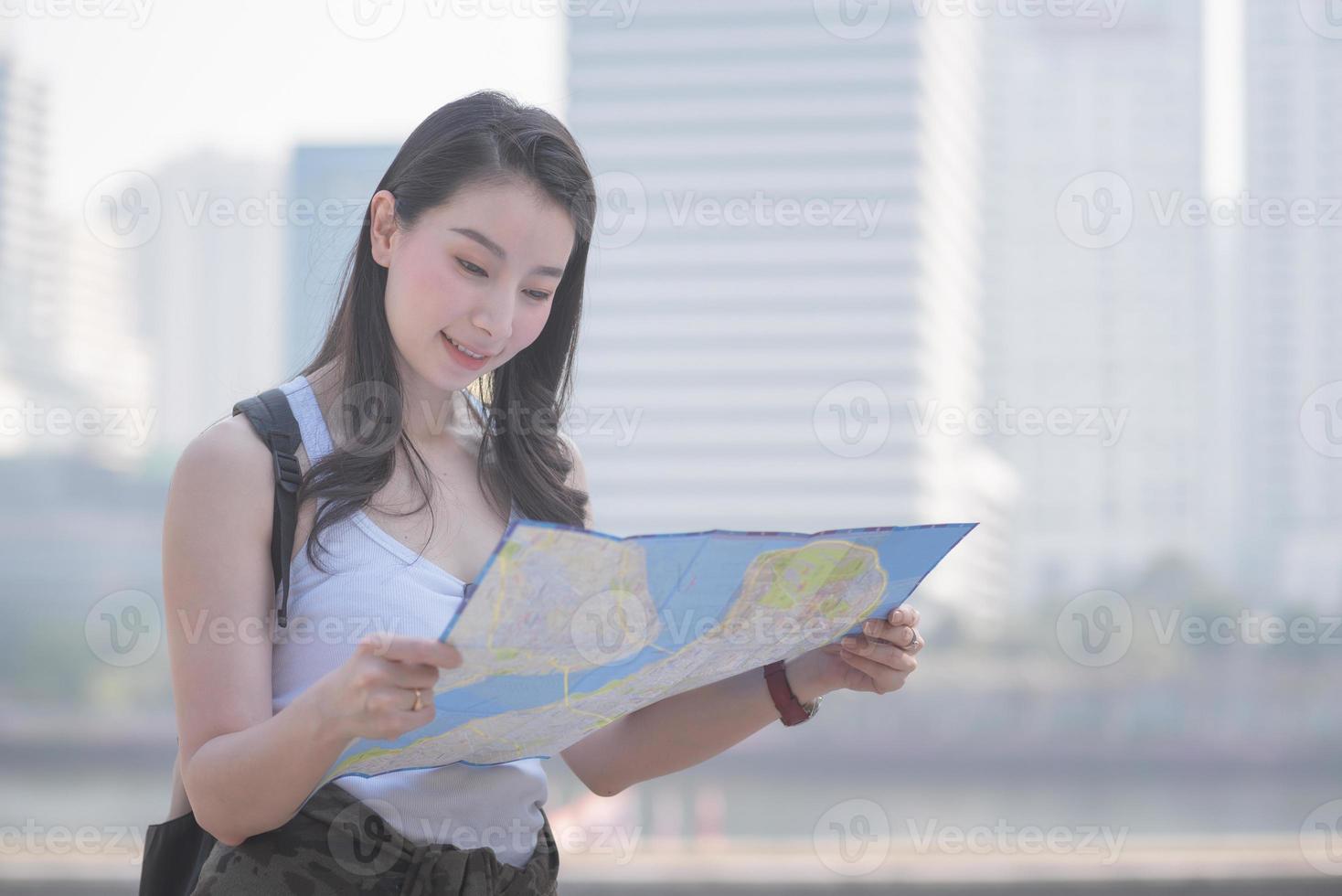 mooie aziatische solo-toeristische vrouw die naar de kaart kijkt op zoek naar toeristen die bezienswaardigheden bezoeken. vakantie reizen in de zomer. foto