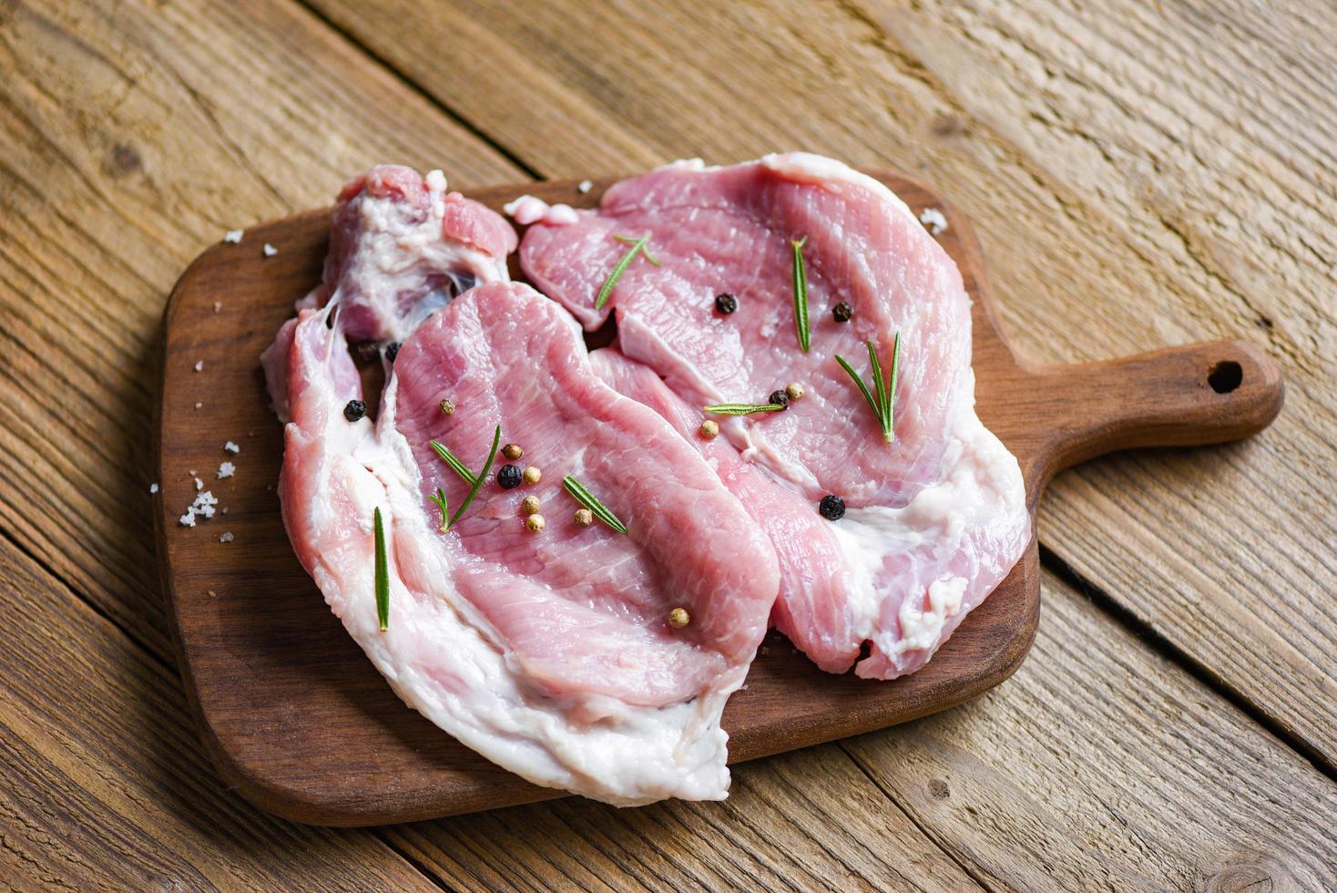 rauw varkensvlees rozemarijn met kruiden en specerijen op houten bord vers varkensvlees foto