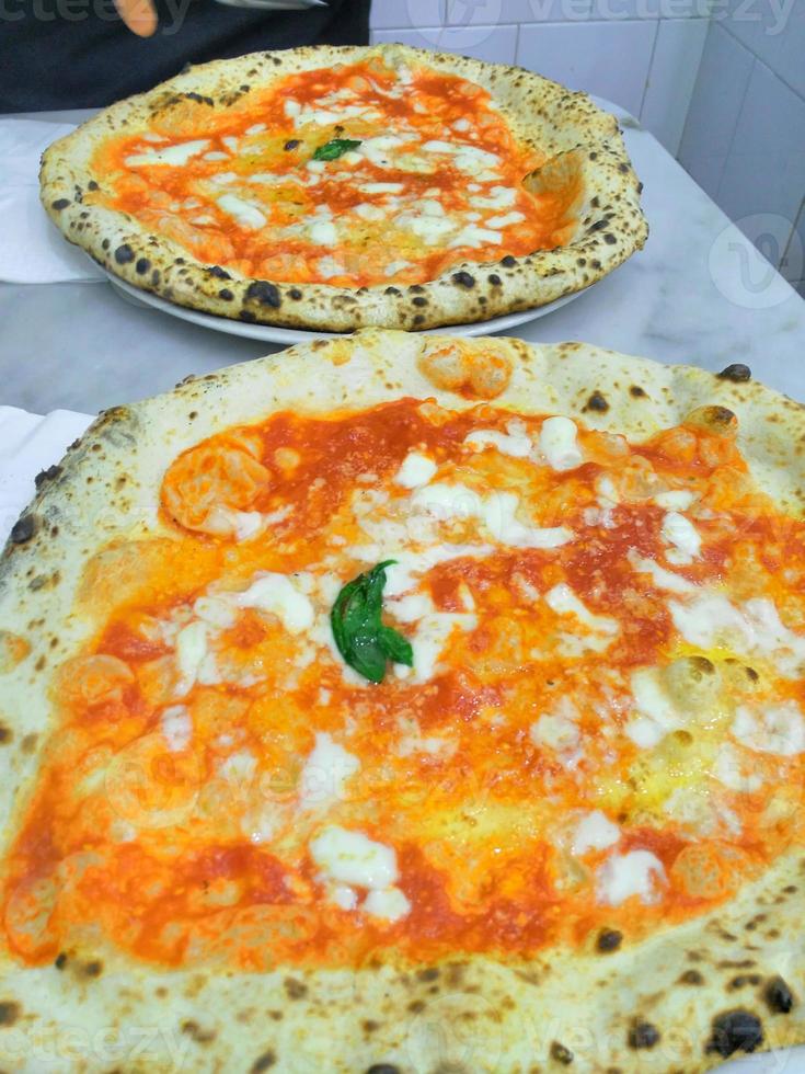 pizza smakelijke hete pepperoni bedekt plakjes koken ingrediënten tomaten met prosciutto en rode tomaat kruiden op tafel. foto
