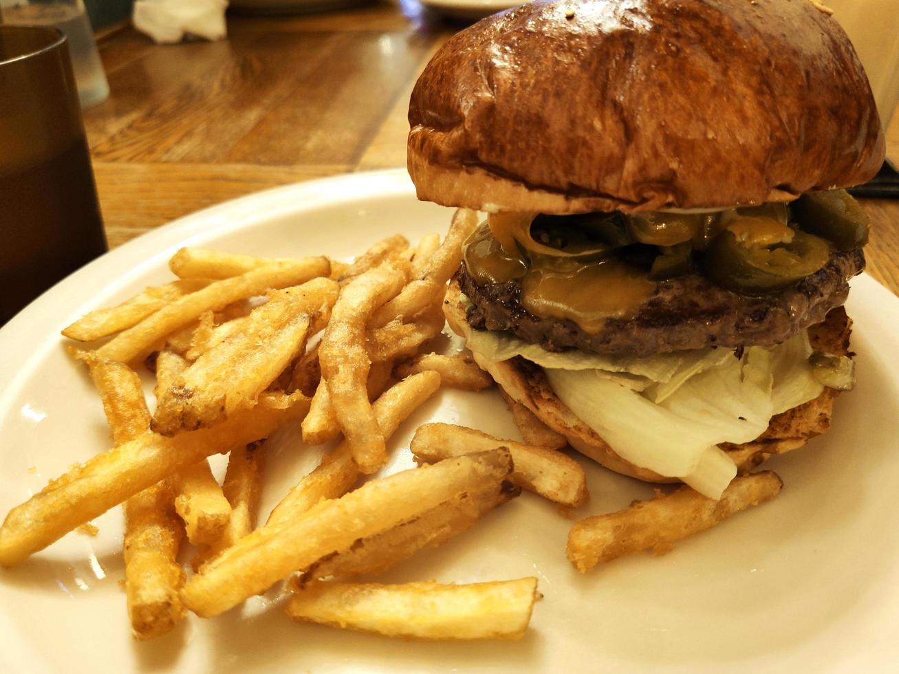 vers straatvoedsel rundvlees hamburger met bruin groenten, kaas en sauzen gebakken frietjes op witte plaat. Stockfoto