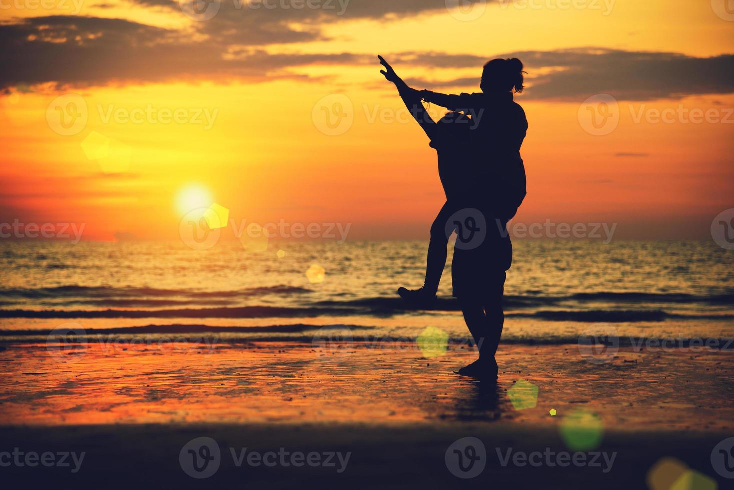 Aziatische geliefden blij op het strand met een prachtige zonsondergang op de achtergrond man die de vrouw optilt. foto