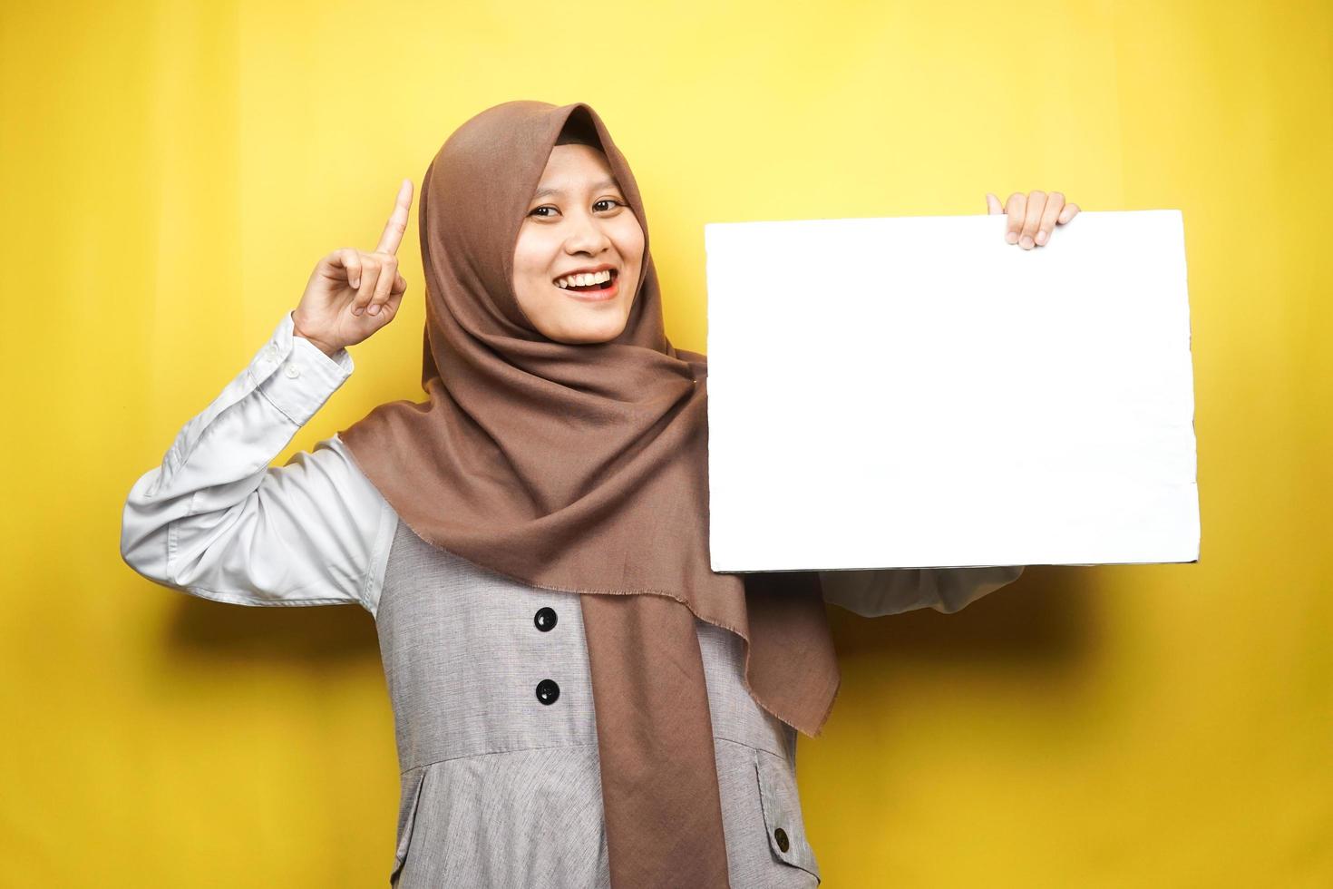 mooie jonge moslimvrouw vrolijk met lege lege banner, plakkaat, wit bord, leeg bord, wit reclamebord, iets presenteren in kopieerruimte, promotie foto