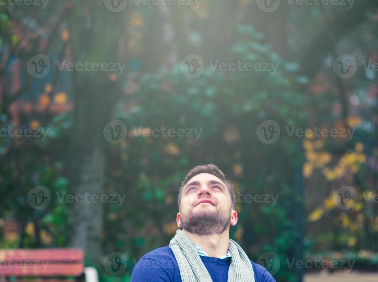 jonge blonde man met kort haar en baard die naar boven kijkt foto