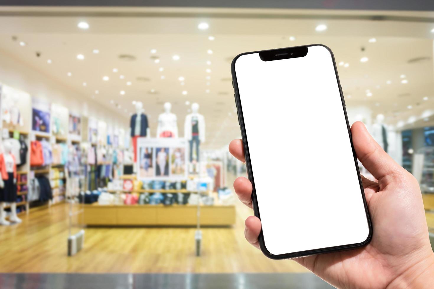 close-up van vrouwelijk gebruik smartphone wazig beelden in het winkelcentrum en kledingwinkel vervagen van de achtergrond. foto