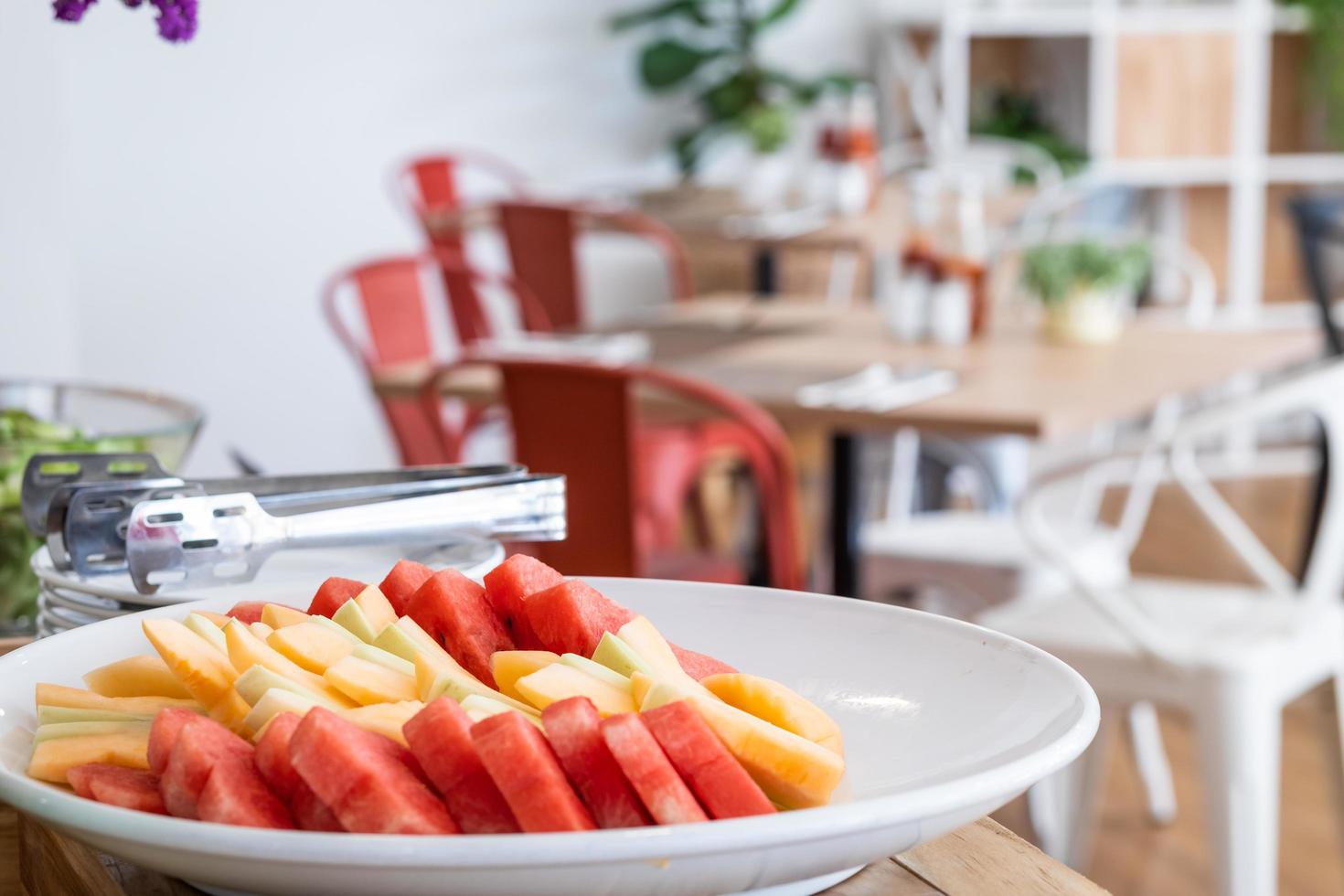 hak de stukjes watermeloen en ananas in witte schaal de eet- en bloemenvaas op tafeldecoratie bij buffet zelfbediening in het hotel. foto
