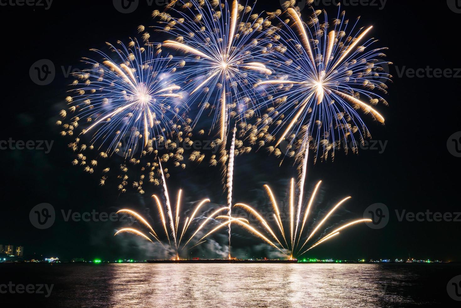 geweldig mooi kleurrijk vuurwerk op de feestavond, te zien op het zeestrand met veelkleurige reflectie op water foto