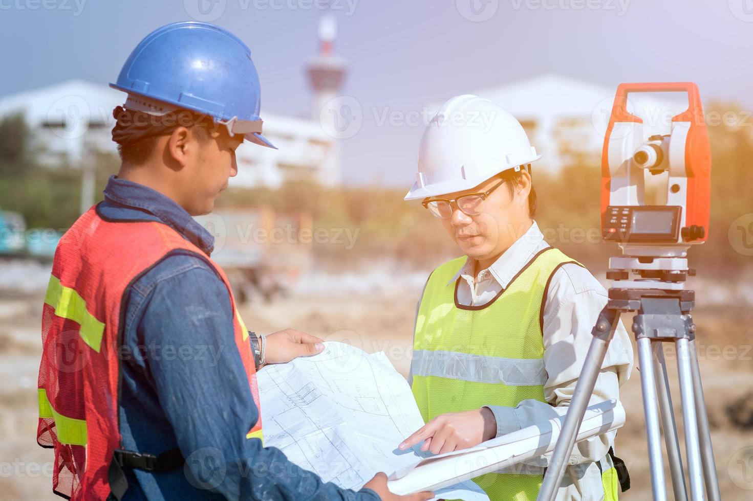 bouwingenieur en voormanarbeider die bouwtekening bij plaats voor nieuw infrastructuurbouwproject controleren foto