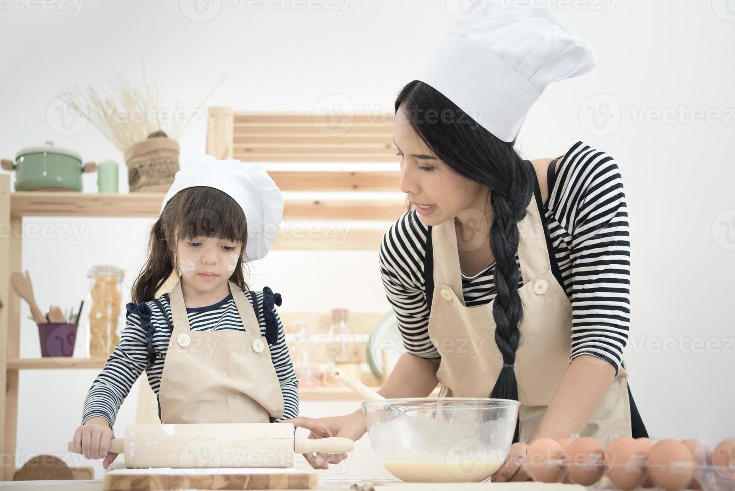 Aziatische moeder en haar dochter bereiden het deeg voor om een cake te maken in de keukenkamer op vakantie. Fotoreeksen van gelukkig familieconcept. foto