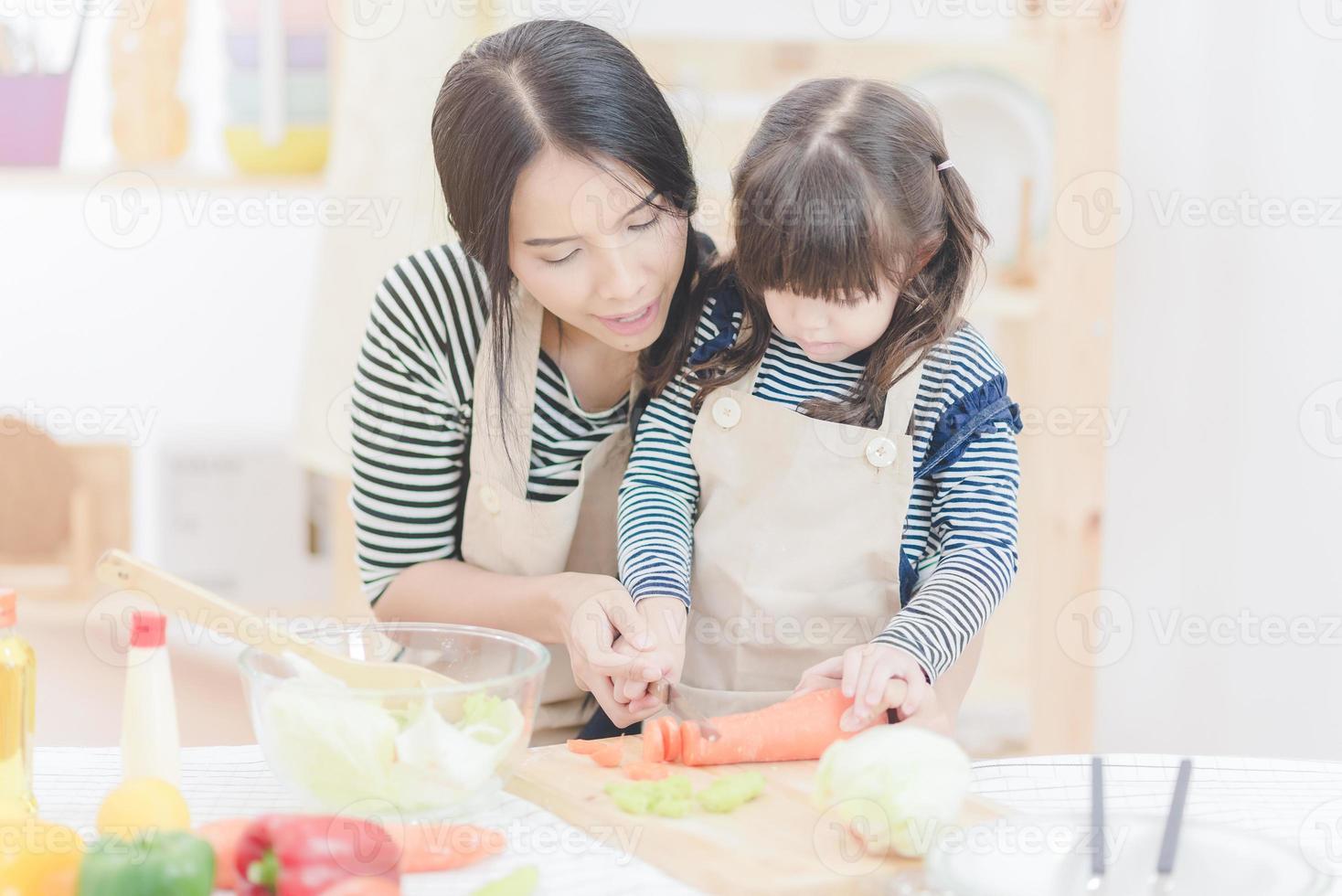 gelukkige liefdevolle familie Aziatische moeder en haar dochter bereiden gezonde voedselsalade in de keukenkamer. Fotoontwerp voor familie, kinderen en gelukkige mensen concept foto