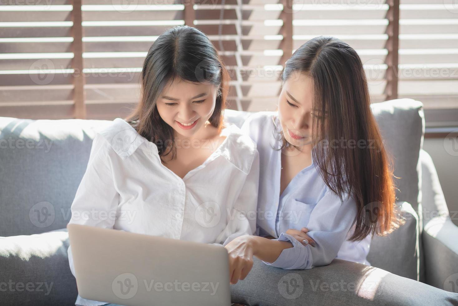 voorwoord Tussendoortje Vulgariteit twee jonge vrouwen gebruiken een laptop om online te winkelen via internet  terwijl ze thuis veilig blijven 4886828 Stockfoto