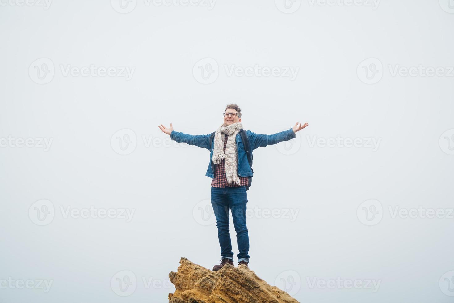 reiziger man met een rugzak staande op de top van de bergtop met handen omhoog in de lucht foto