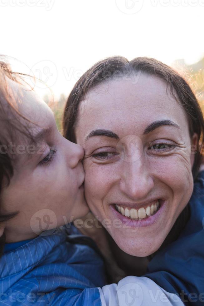 jongen kusjes en knuffels mama, gelukkig moederschap foto