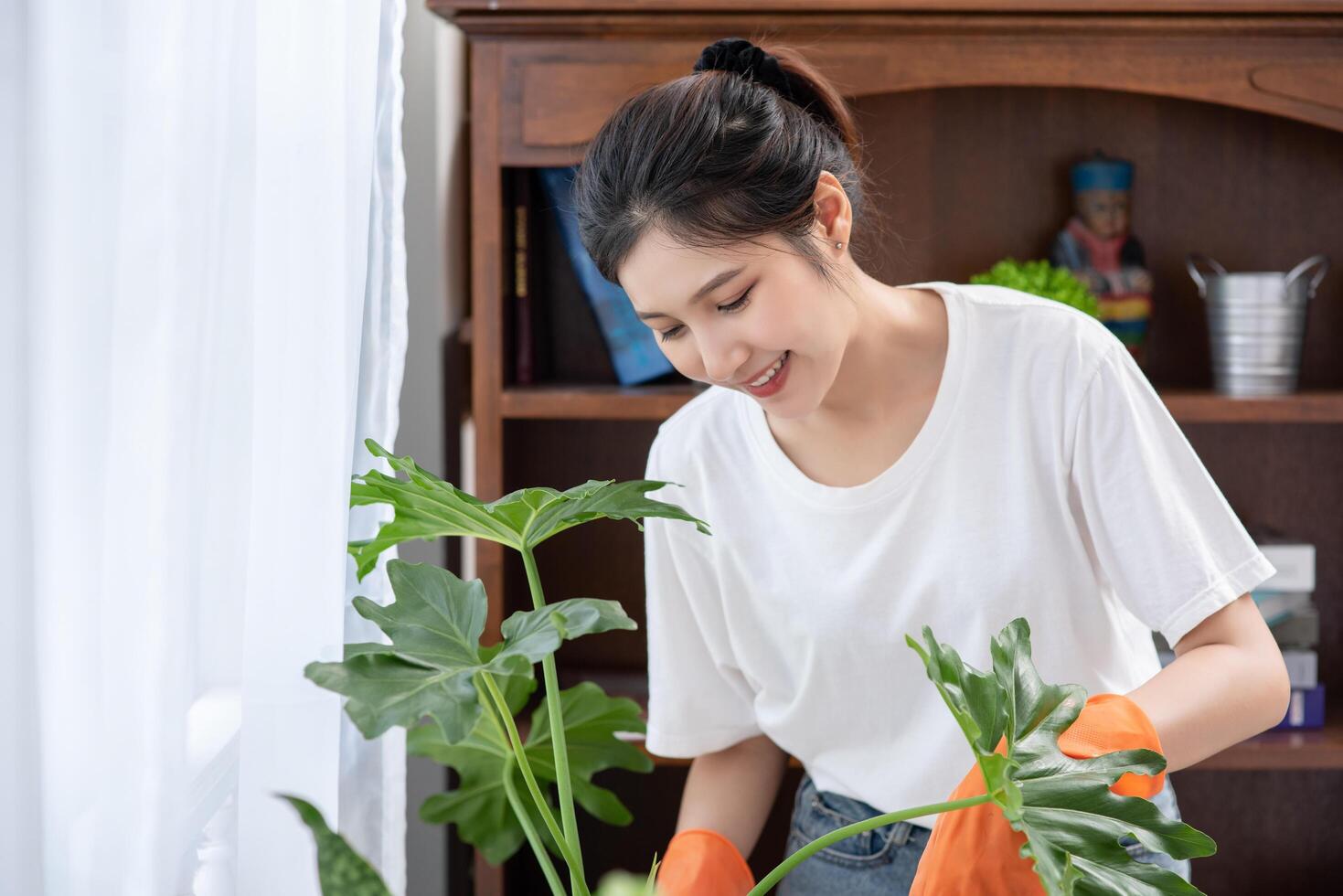 de vrouw droeg oranje handschoenen en plantte bomen in het huis. foto