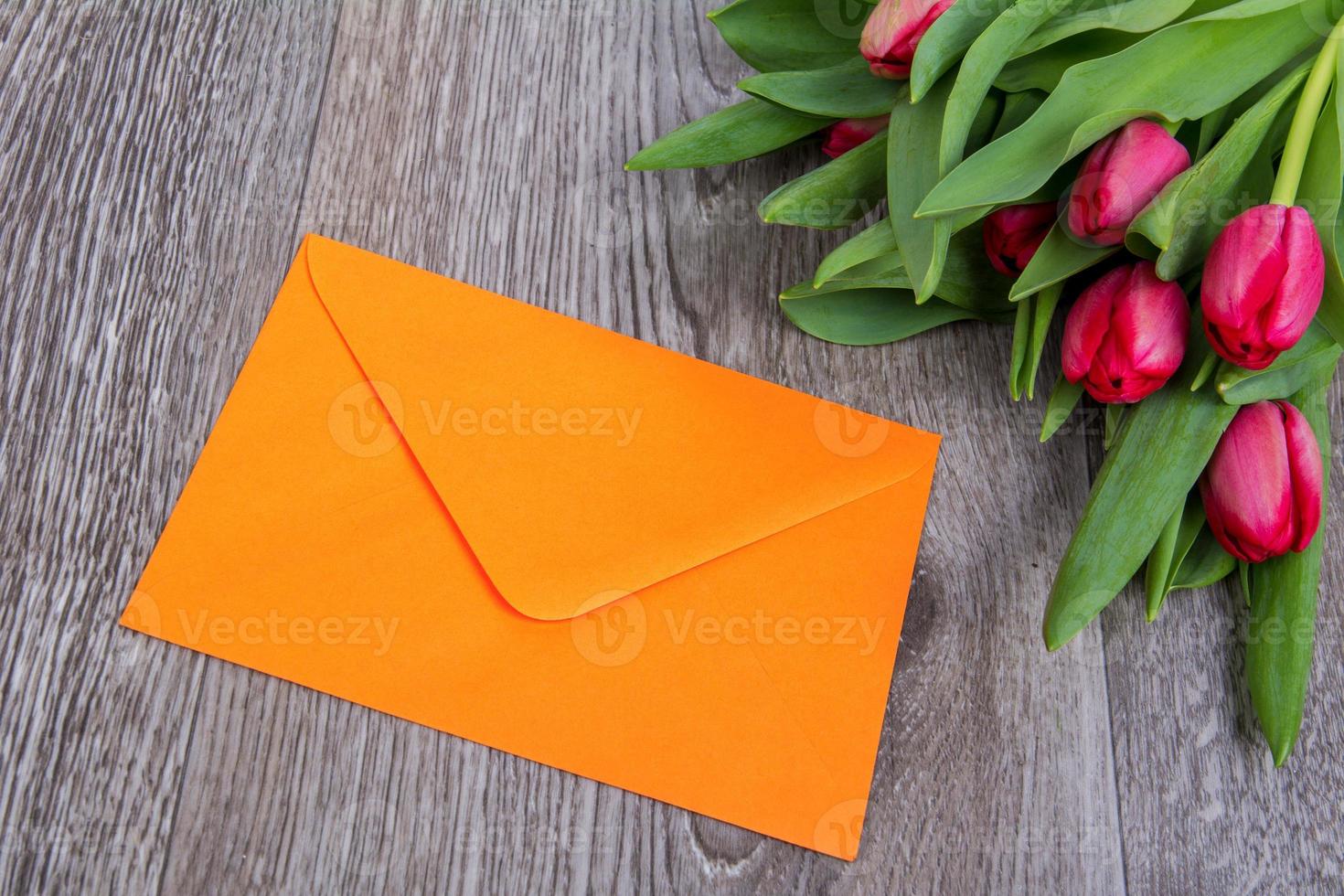 roze envelop met tulpen op een houten tafel foto