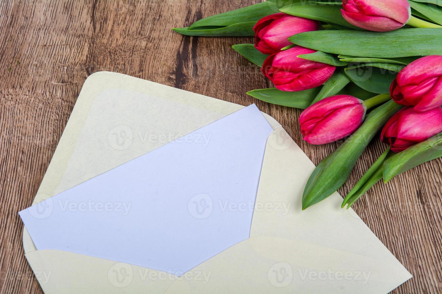 roze envelop met tulpen op tafel foto