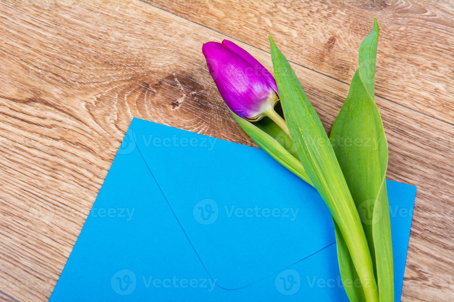 blauwe envelop met tulpen op tafel foto