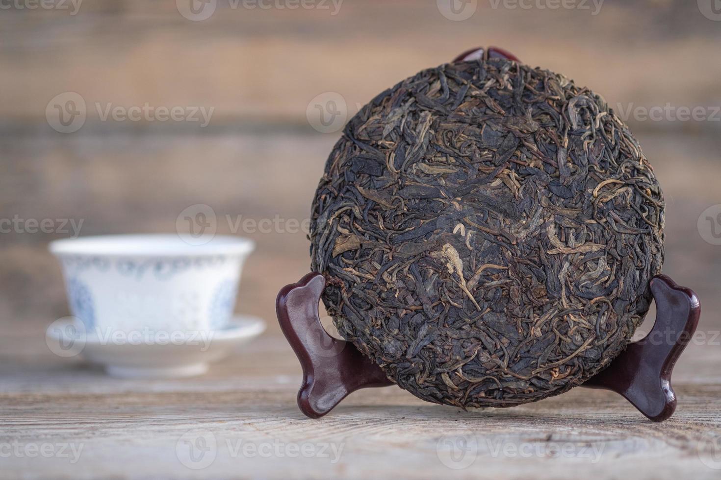 traditionele chinese pu-erh thee op een houten standaard. rauwe gefermenteerde thee in de vorm van een pannenkoek foto