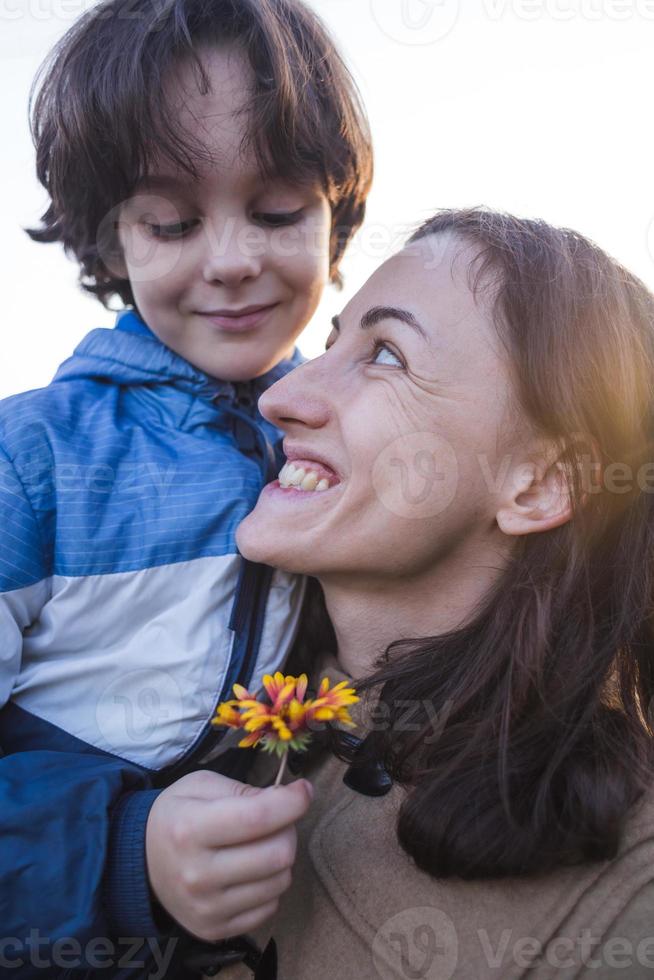 een kind geeft een bloem aan zijn moeder foto